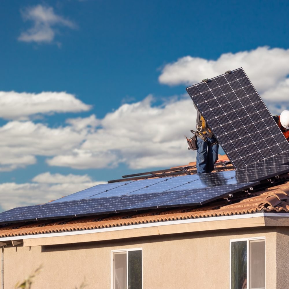 Workers Installing Solar Panels on House Roof